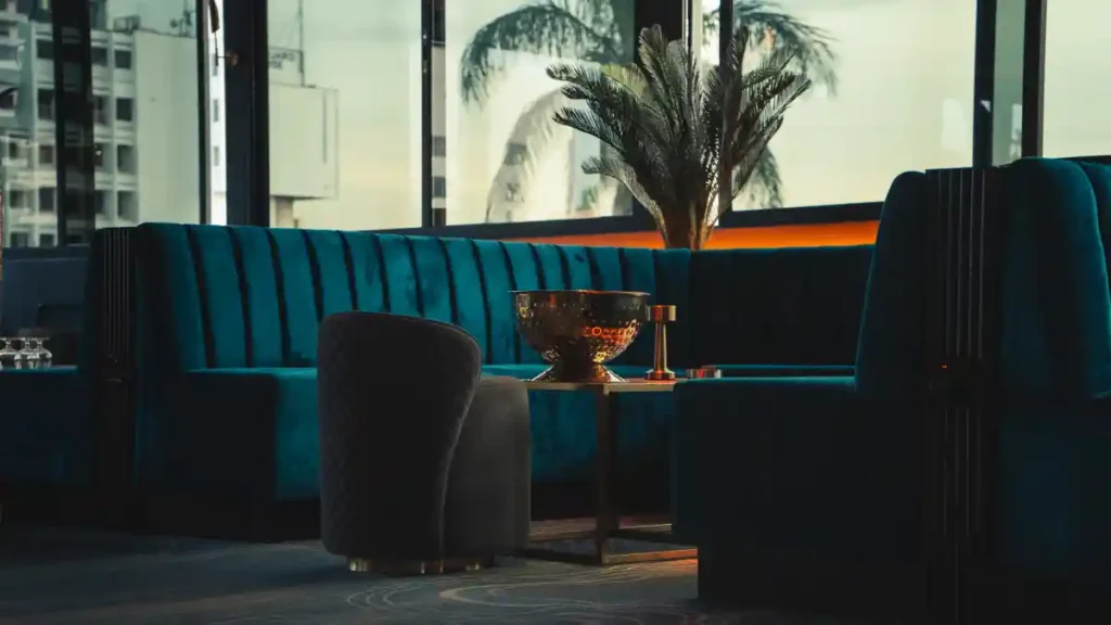 Teal velvet banquette seating at Ciel Nairobi with a gold champagne bowl by the terrace window